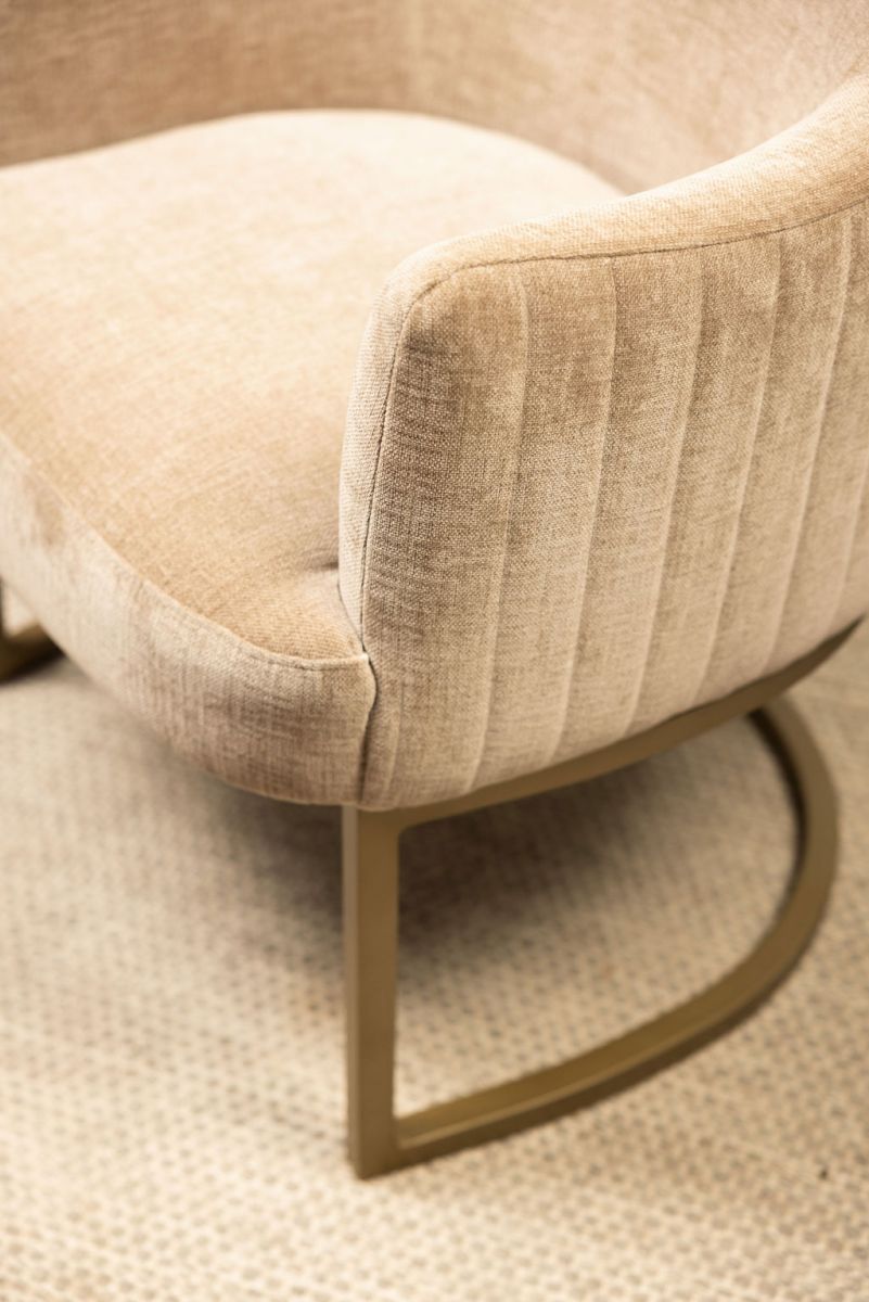 modern armchair in stone with brushed bronze metal base 